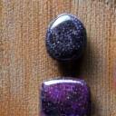 Smooth, polished amethyst and black tourmaline stones on a rustic wooden table, with soft, serene lighting, suggesting stress relief.