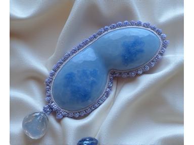 Illustration of moonstone and lepidolite crystals on a silken cloth beside a sleeping person, representing sleep optimization.